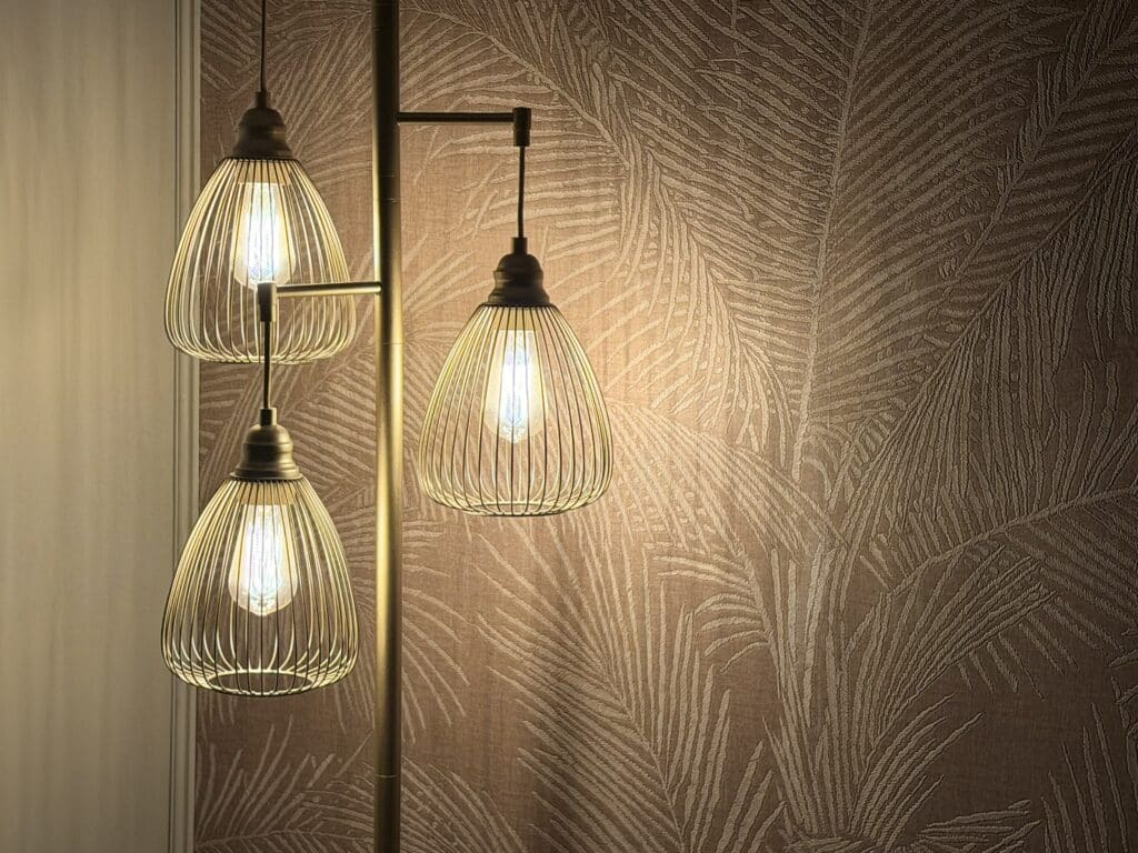 Warm glow from vintage-style pendant lights on palm leaf wallpaper - Suma Interiors